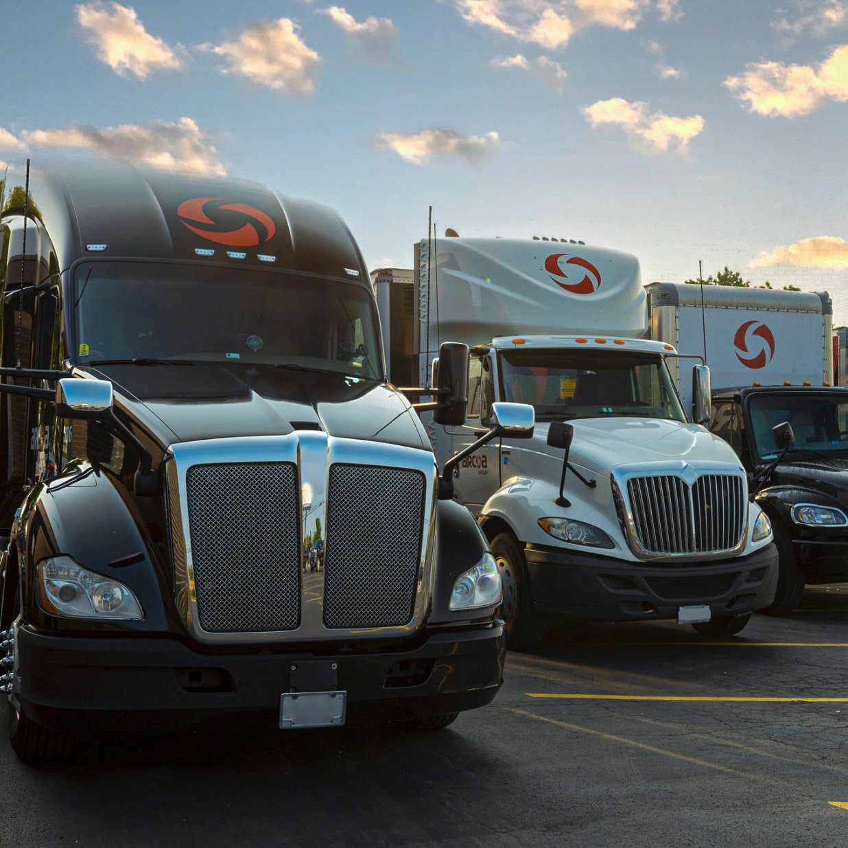 4 ARCOA trucks parked side by side at an angle in outdoor parking lot on a sunny day